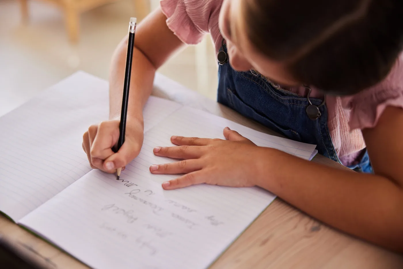 Child writing in notebook during homeschool lesson